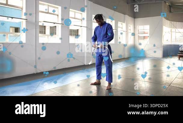 Martial arts student holding belt in gi unfolding tying knot with ...
