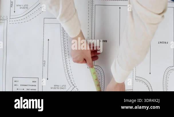 Seamstress uses measuring tape to check exact size of pattern pieces ...