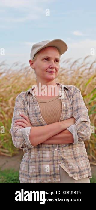 Confident female farmer standing with crossed arms near cornfield at ...