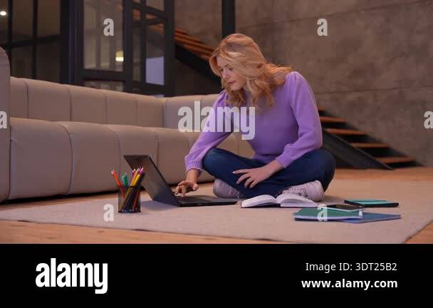 Pensive adorable blonde teenage girl sitting cross legged on floor ...