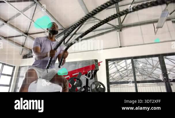 Man lifting battle ropes in gym and activating animated green cloud ...
