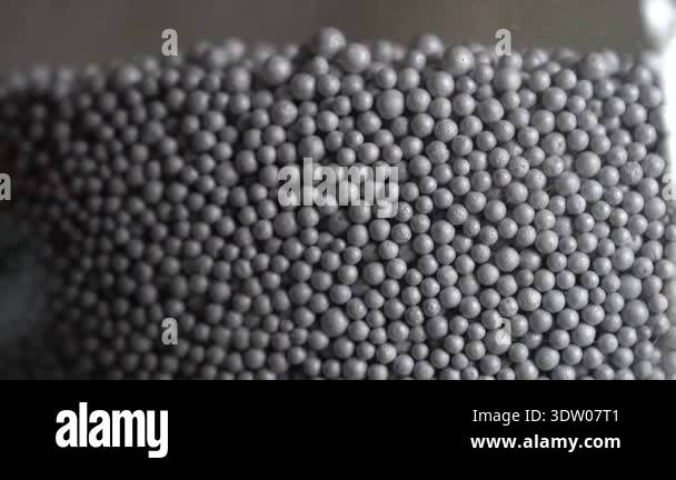 Close-up of gray spherical particles inside a clear container ...
