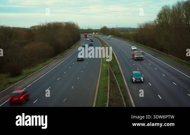 Highway traffic flowing along multi lane motorway with cars and trucks ...