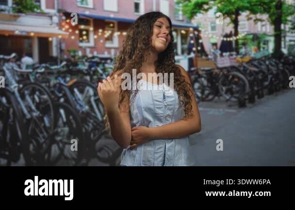 Hispanic teenage woman touching hair with right hand, smiling and ...
