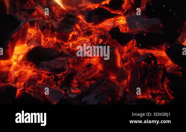 Close up of glowing charcoal embers with orange heat and flying sparks ...
