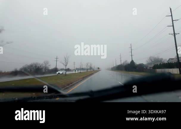 Driving on a rainy suburban road during heavy rain with poor visibility ...
