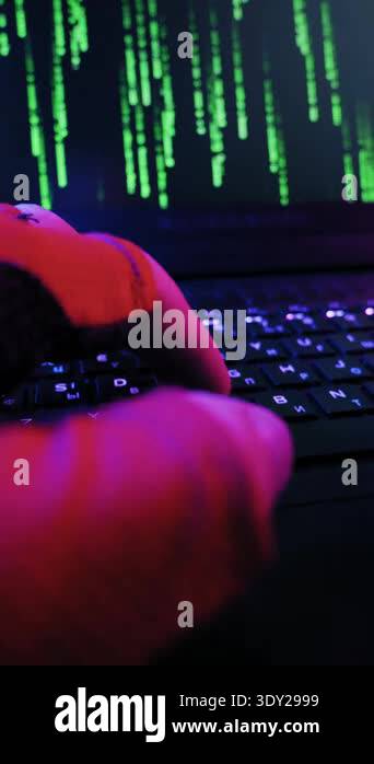 Gloved hands type quickly on a backlit laptop keyboard. Green matrix ...