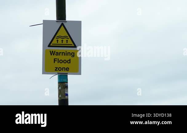 Warning sign with text Warning Flood zone mounted on pole against ...