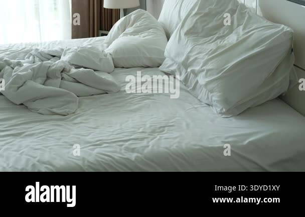 Unmade bed with rumpled white sheets and pillows, illustrating the ...