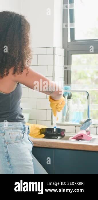 A Black woman with beautiful natural hair diligently washes dishes in a ...