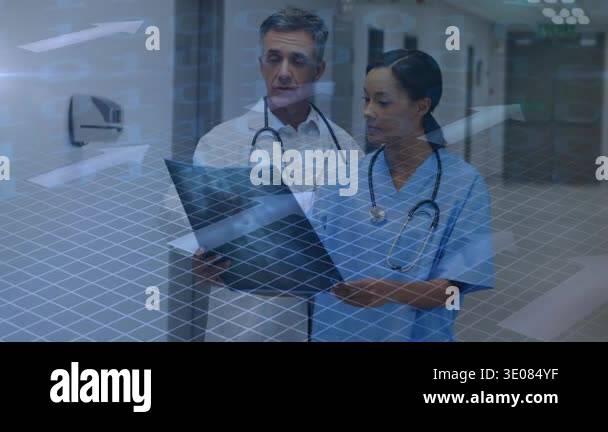 Dr and nurse stopping in hospital, reviewing chart for care, pointing ...