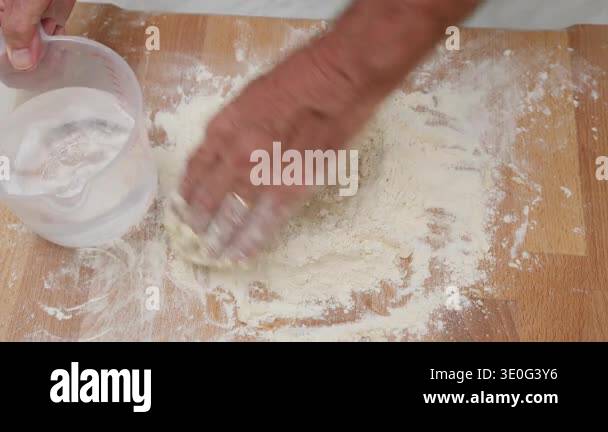 water-and-flour-to-prepare-homemade-pasta-on-a-wooden-cutting-board