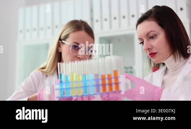 Concentrated women hold plastic rack with test tubes full of color ...