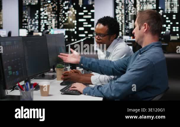 Team of technicians collaborating in office, typing code on computer ...