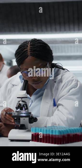 Someone Using Optical Microscope Vertical video Female scientist using optical microscope to study ...