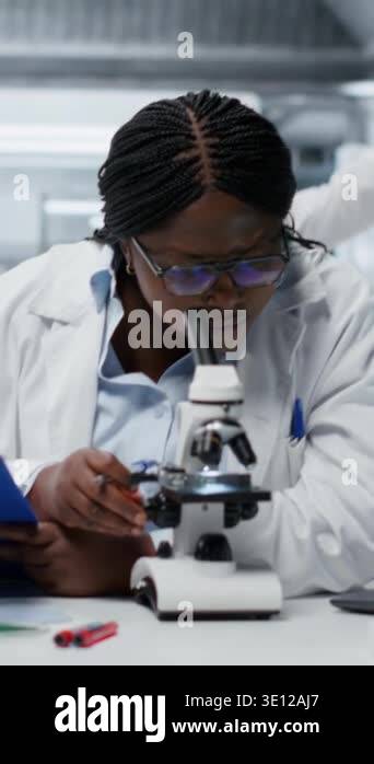 Someone Using Optical Microscope Vertical video Female scientist using optical microscope to study ...