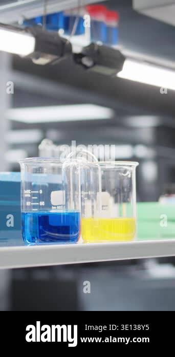 Vertical video Close up of laboratory glassware filled with blue and ...