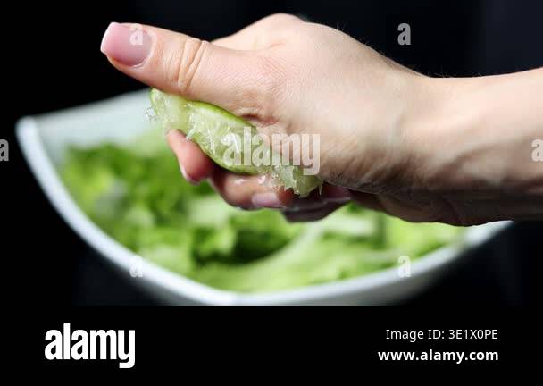 Splash of lime juice close up in slow motion. Hand squeezing half of a ...