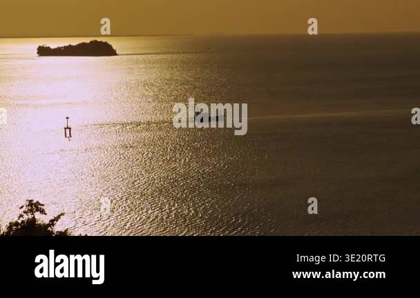 Distant View Of Boat Moving Across Golden Sea At Sunset With Island ...