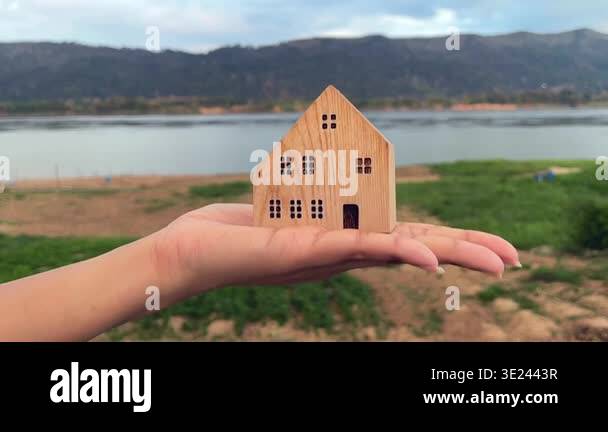 Slow motion of hand holding small wooden house model with beautiful ...