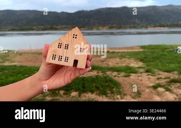 Slow motion of hand moving small wooden house model gently with ...