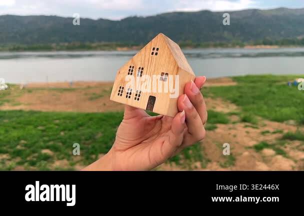 Slow motion of hand moving small wooden house model gently with ...