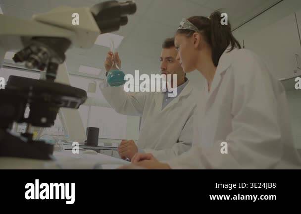 Male lab scientist lifting flask, analyzing blue sample while math ...