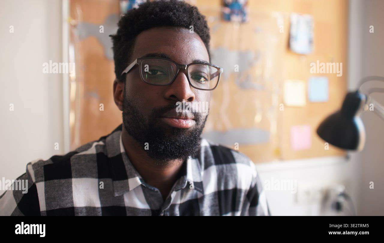 Portrait of young smiling black man wearing glasses looking at camera ...