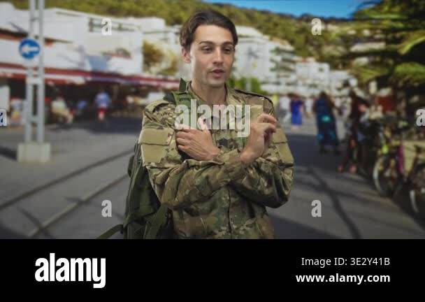 Soldier man in camouflage uniform with dogtags and backpack points ...