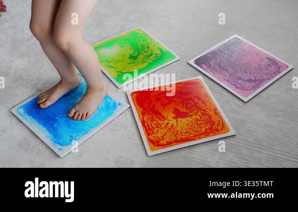 Child feet standing on colorful sensory gel mat on floor during tactile ...