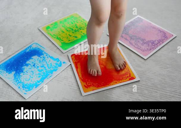 Child feet standing on colorful sensory gel mat on floor during tactile ...
