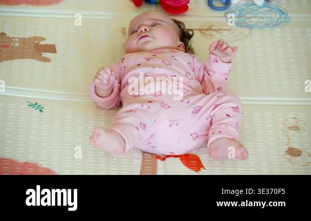 Baby lying on a play mat surrounded by colorful toys during playtime ...