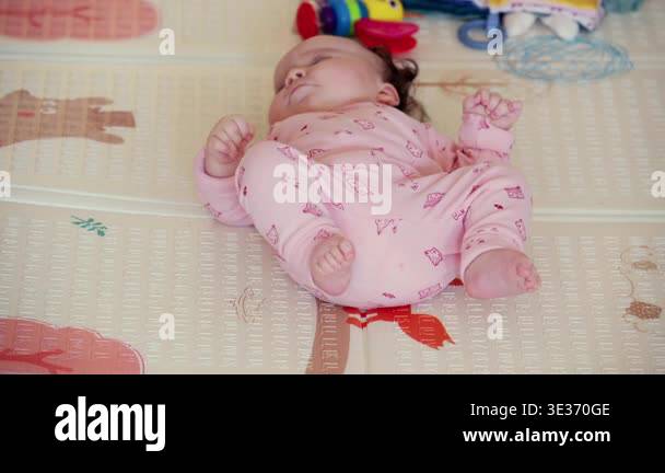Baby lying on a play mat surrounded by colorful toys during playtime ...