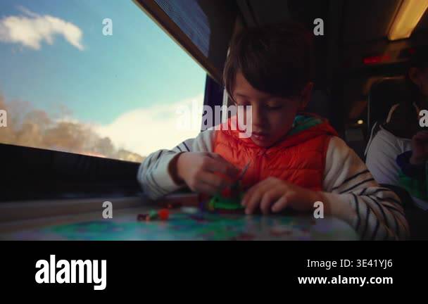 Boy absorbed in creative play inside carriage as woman keeps younger ...