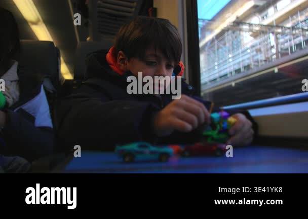 Child pushes small toy car and figures along cabin table on moving ...