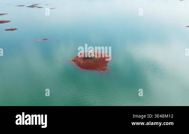 Aerial view of a small red earth island with a solitary structure ...