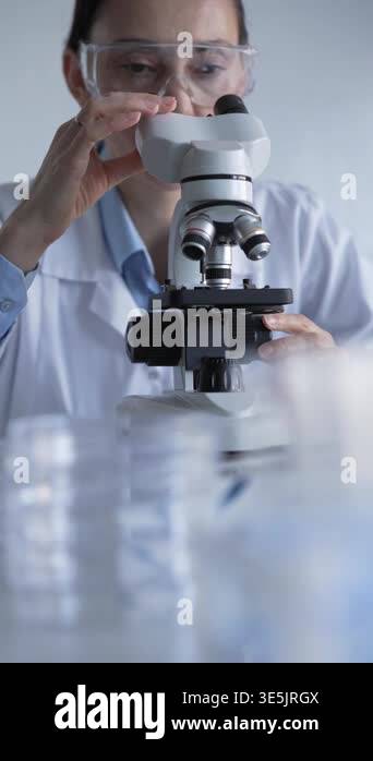 Woman scientist wearing lab coat and protective glasses is using ...