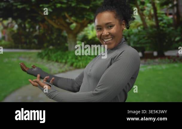 Young african american woman smiling and presenting open hands palm up ...