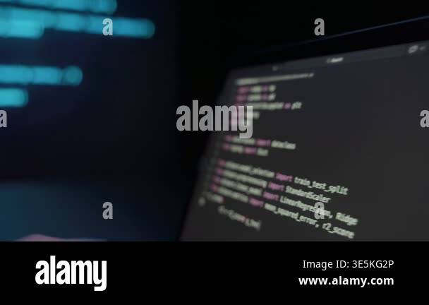 Focused software engineer writing script on computer in dark room late ...