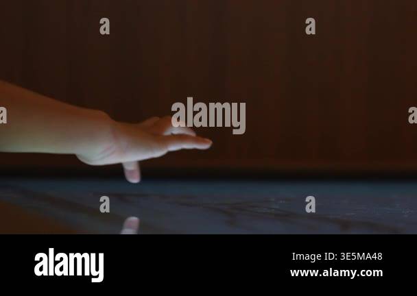 Child hand touching an illuminated interactive surface with reflection ...