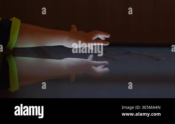 Child hand touching an illuminated interactive surface with reflection ...