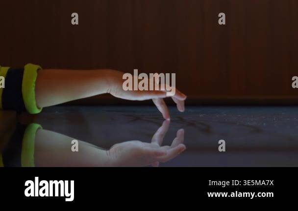 Child hand touching an illuminated interactive surface with reflection ...