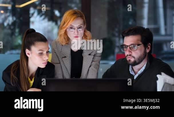 Four professionals focus on a computer screen in an office. They work ...