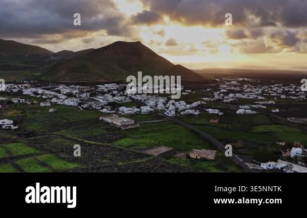Two mountains rise under a yellow and orange sky at sunset in Lanzarote ...