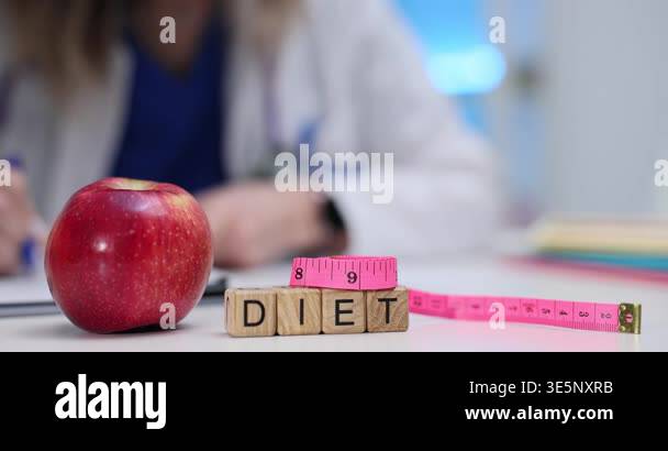 Wooden blocks spell word Diet on clinic desk. Red apple and pink ...
