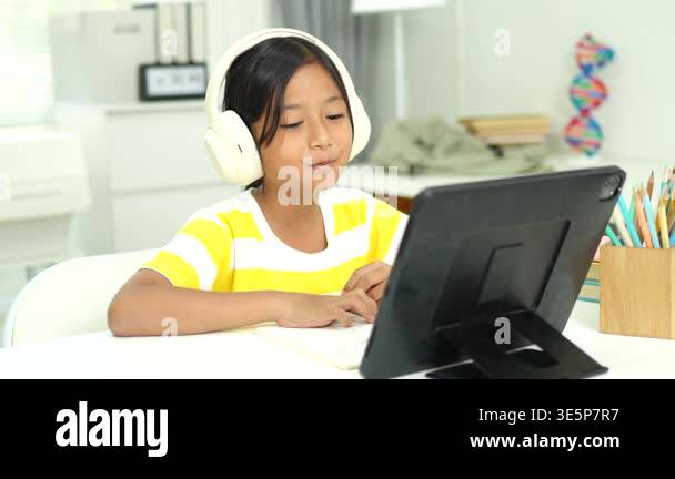 Elementary school girl wireless headphones and watching an interactive ...