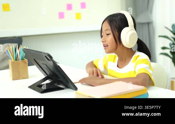 Elementary school girl wireless headphones and watching an interactive ...