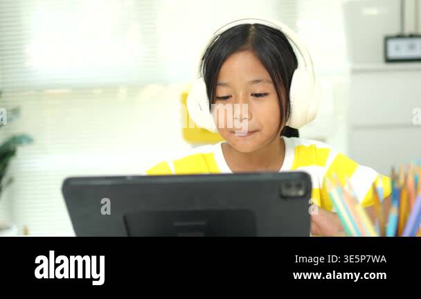Elementary school girl wireless headphones and watching an interactive ...