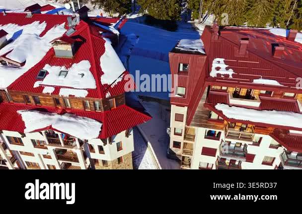 Snow rests on the roofs of buildings in a ski resort area. The scene ...