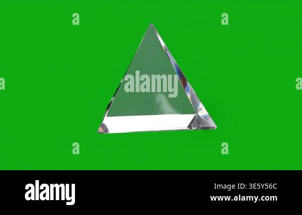 A clear glass pyramid rotates slowly on a solid green screen background ...